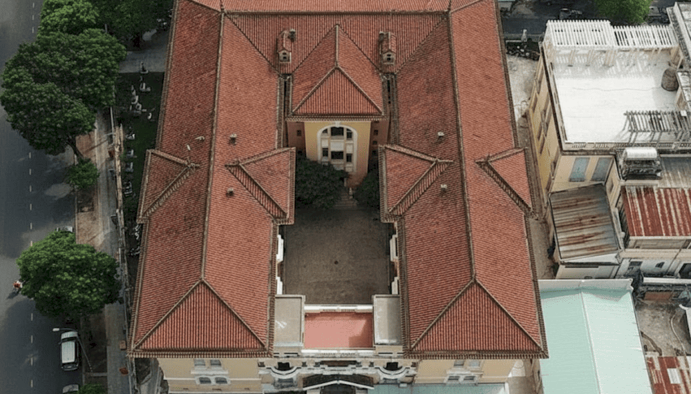 The Art Deco building blends Asian traditions with Western modernity, featuring a red yin-yang tiled roof symbolic of Vietnamese architecture